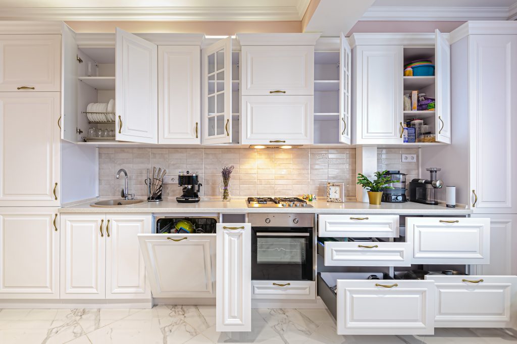 Luxury modern white kitchen interior with open doors and drawers