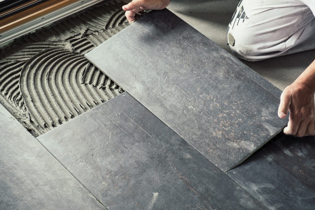 worker laying down ceramic floor tiles