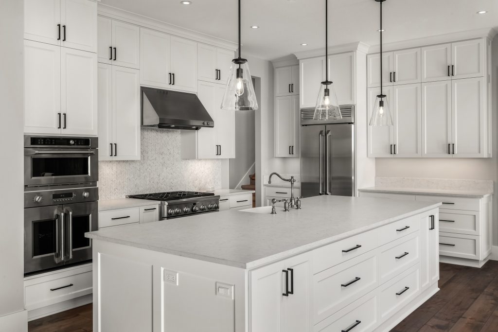 Beautiful kitchen in new luxury home with stainless steel appliances, pendant lights, and hardwood floors