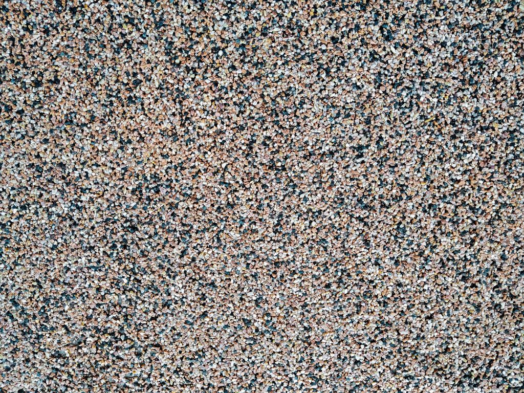 Close up of decorative quartz-filled epoxy sand epoxy coated floor or wall coating with grey, black and white coloured particles. Copy space.