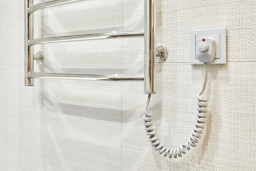 Modern heated towel rail on tiled socket bathroom wall
